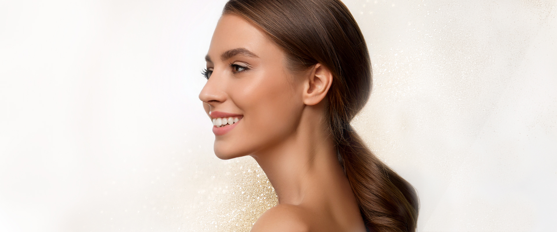 Bild einer attraktiven jungen Frau in Seitenansicht, dezent im Hintergrund sieht man einen Schimmer von Goldpartikeln